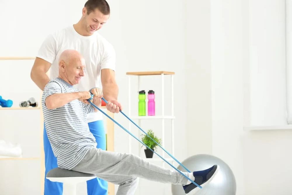 terapeuta apoyando a paciente mayor con banda elastica y bola de ejercicio en sesion de rehabilitacion terapeuta apoyando a paciente mayor con banda elastica y bola de ejercicio en sesion de rehabilitacion