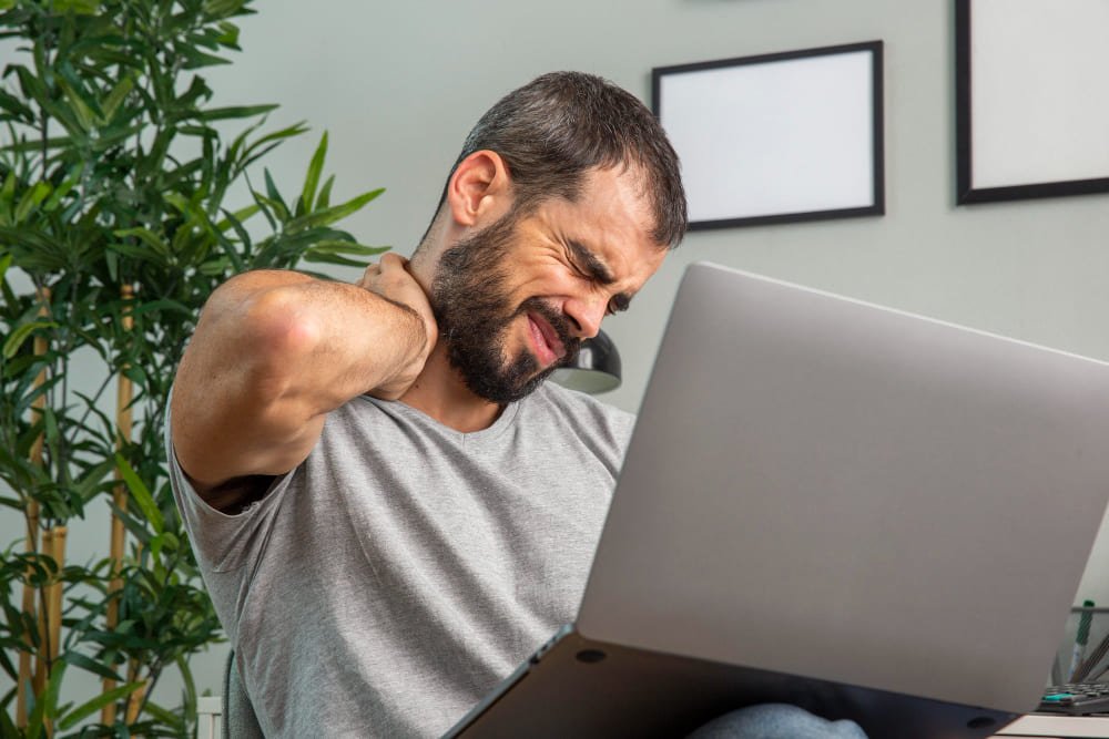hombre con dolor de cuello frustrado frente a un portatil hombre con dolor de cuello frustrado frente a un portatil