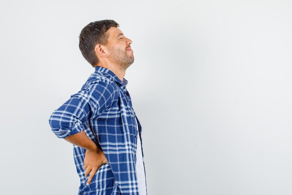 varon adulto con camisa cuadros sujetandose la espalda dolor lumbar y postura incomoda varon adulto con camisa cuadros sujetandose la espalda dolor lumbar y postura incomoda